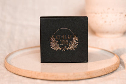 Resting on a ceramic plate sits a black jewellery box with the logo of coffee bean culture